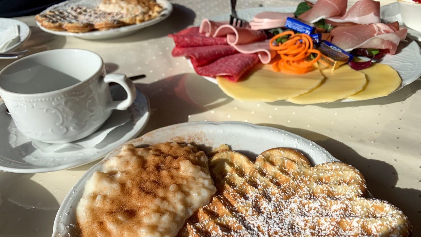 Gedeckter Tisch mit Waffeln, Reisbrei, Aufschnitt und Kaffeetasse